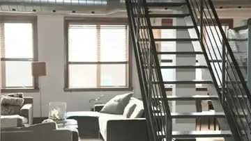 industrial style loft apartment with exposed ventilation and large windows and staircase